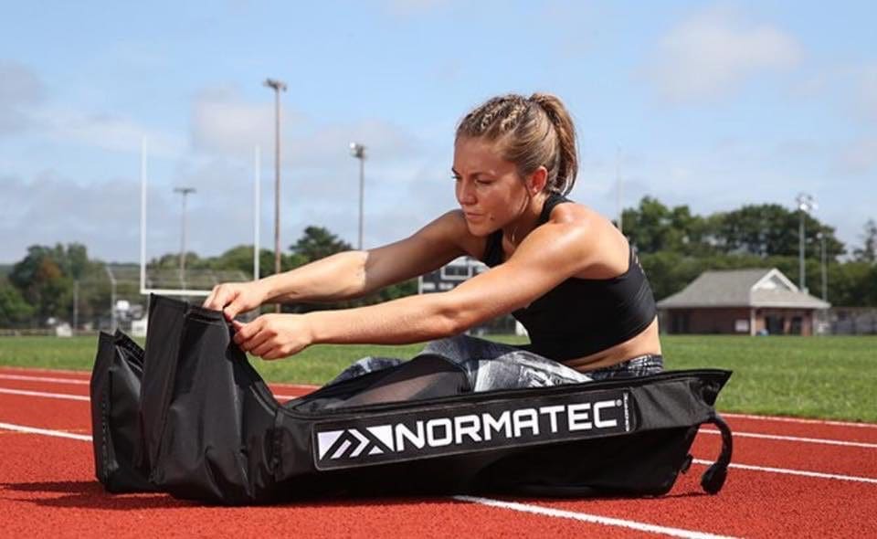 female athlete using Normatec compression therapy on a track